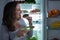 Woman Eating Donut In Front Of Fridge