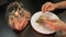 Woman is eating dried fish in kitchen, close up. Person cleans and eats salted dried fish in night