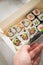 Woman eating edamame, salmon, surimi, cucumber and avocado Maki and inside out California sushi with soy sauce, pickled ginger,