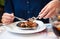 Woman eating escargot with special fork and tongs