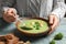 Woman eating fresh vegetable detox soup made of broccoli with croutons at table