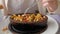 Woman is eating frying hot shrimps with vegetables served in clay bowl, closeup dish.