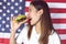 Woman eating hamburger with background of american flag
