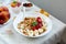 Woman eating healthy breakfast bowl, hold in hand granola, seeds, fresh strawberry, banana, top view, copy space.