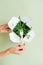 Woman eating pea sprout from paper box with bamboo fork. Hands only