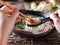 Woman eating pho with sriracha using chopsticks and spoon together