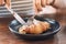 A woman eating a piece of croissant by knife and fork