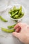 Woman eating portion Japanese Edamame soy beans in plastic take away tray bowl