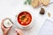 Woman eating red borscht with vegetables, meat and sour cream