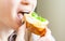 Woman eating sandwich with cheese and green vegetables onion