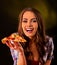 Woman eating slice of Italian pizza . Student consume fast food.