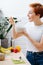 Woman eating spoonful of muesli, while standing next to kitchen high table