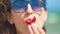 Woman eating strawberries near sea on sunny summer day. Closeup.