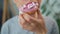 Woman eating sweet pink donut with marshmallows. Close-up