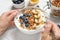 Woman eating tasty yogurt with oatmeal, banana and blueberries at white wooden table