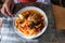 Woman eats homemade chicken cacciatore with pasta  and mushrooms in tomatoe sauce. Plate with chicken spagetti cacciatore on dinni