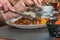 A woman eats a hot meat dish in a restaurant. Lamb kabob with fresh vegetables and fried potatoes