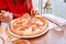 Woman eats with knife and fork a pizza capricciosa. Pizza with mozzarella tomatoes, Artichoke, black olives and basil