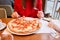 Woman eats with knife and fork a pizza capricciosa. Pizza with mozzarella tomatoes, Artichoke, black olives and basil