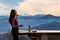 Woman eats sandwiches and drinks tea against landscape with mountains