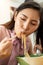 Woman eats spicy hot tomyum noodle soup and hanging on chopstick