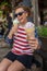 Woman eats two waffle ice cream cones, sitting down, smiling, wearing patriotic american USA clothing and sunglasses