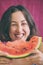A woman eats a watermelon and laughs