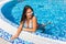 woman at the edge of swimming pool in bikini