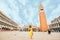 woman in elegance yellow sundress with straw bag walking by Venice saint marco square