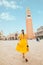 woman in elegance yellow sundress with straw bag walking by Venice saint marco square