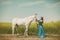 Woman in elegant long dress with gorgeous white horse