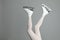 Woman in elegant white ice skates on grey background, closeup of legs. Space for text