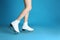Woman in elegant white ice skates on light blue background, closeup of legs. Space for text
