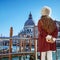 Woman on embankment in Venice, Italy holding Venetian mask
