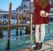 Woman on embankment in Venice, Italy holding Venetian mask