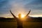 Woman embracing life standing outside in beautiful meadow with her arms raised high