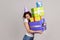 Woman embracing lot of birthday gifts and smiling joyfully, celebrating, admiring many presents.