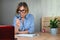 Woman emotionally looking at laptop screen through magnifier