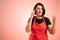 Woman employed at supermarket with red apron and black t-shirt happy face and gestures and talking on cellphone