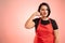 Woman employed at supermarket with red apron and black t-shirt showing call me gesture