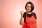 Woman employed at supermarket with red apron and black t-shirt showing fist