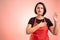 Woman employed at supermarket with red apron and black t-shirt showing oath