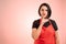 Woman employed at supermarket with red apron and black t-shirt showing shh gesture