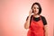 Woman employed at supermarket with red apron and black t-shirt talking on cellphone