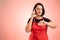 Woman employed at supermarket with red apron and black t-shirt talking on cellphone watching time