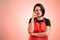 Woman employed at supermarket with red apron and black t-shirt wondering