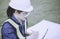 Woman engineer or architecture checking chack list or inspection data in clipboard by ware personal protective equipent ppe at