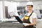 Woman engineer in helmet and coveralls posing in factory.