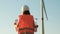 Woman engineer takes off her helmet after work at the station with windmills. Generation of electricity. Alternative