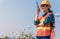 Woman engineer in uniform and yellow safety helmet using radio communication for staff contact to check wind turbine power